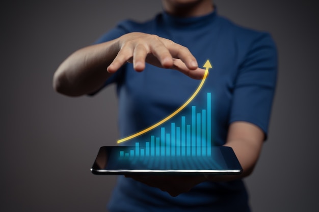 Foto frau, die digitales marketing der tablettplanung mit diagrammhologrammeffekt verwendet