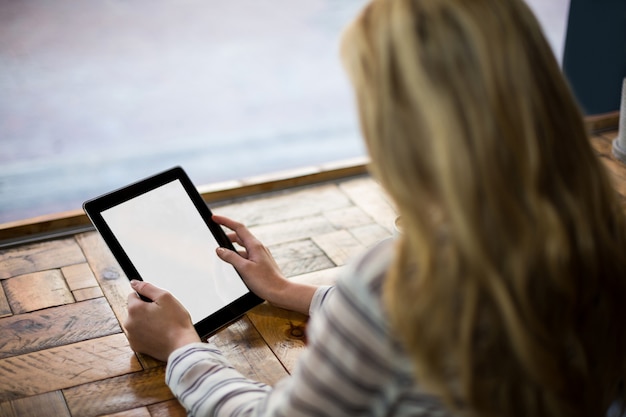 Frau, die digitales Tablett im Kaffee verwendet