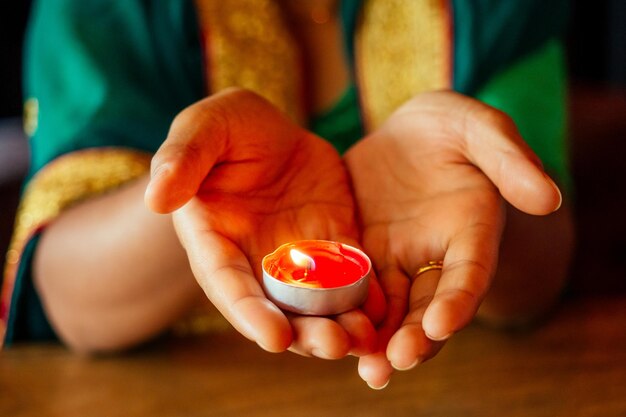 Frau, die Diyas mit Nuth-Nath-Nasenpiercing und dem goldenen Teakholz mit traditionellem Mode-Sari . beleuchtet