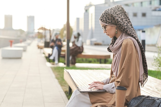 Frau, die draußen am Laptop arbeitet