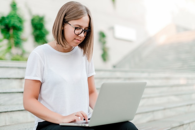 Frau, die draußen an Laptop als freiberuflicher Angestellter arbeitet