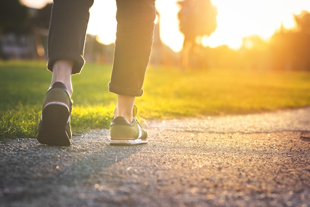 Frau, die draußen im Park spazieren geht Schuhe mit aufgerollten Jeans Einen Schritt machen Neues Lebenskonzept