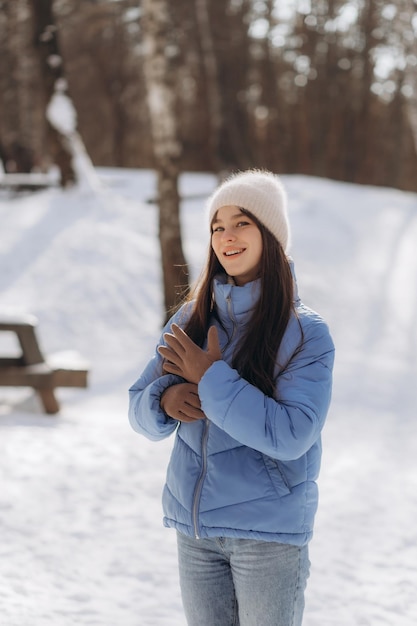 Frau, die draußen im Winterwald stylische Handschuhe anzieht