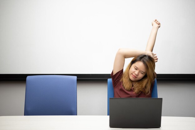 Frau, die durch Laptop im Büro mit Entspannung arbeitet