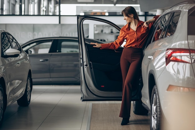 Frau, die ein Auto in einem Autosalon wählt