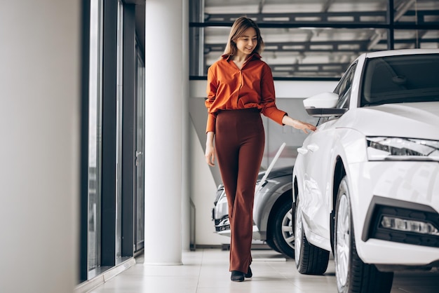 Frau, die ein Auto in einem Autosalon wählt