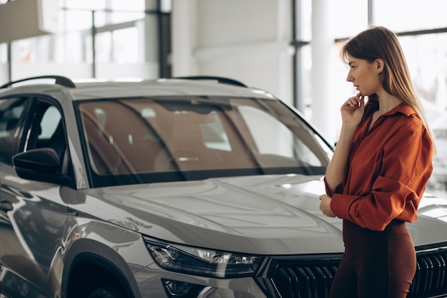 Frau, die ein Auto in einem Autosalon wählt