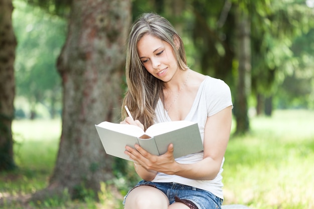 Frau, die ein Buch am Park liest