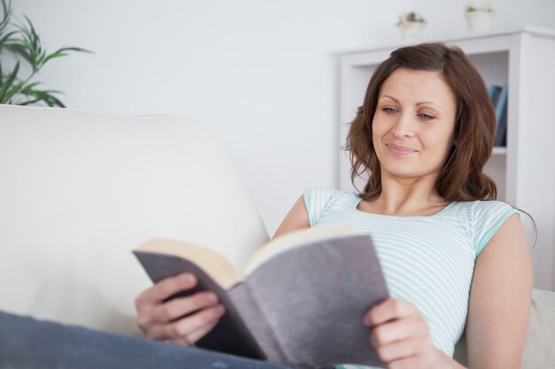 Frau, die ein Buch auf einem Sofa liest