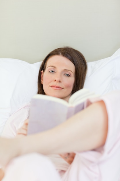 Frau, die ein Buch auf ihrem Bett liest