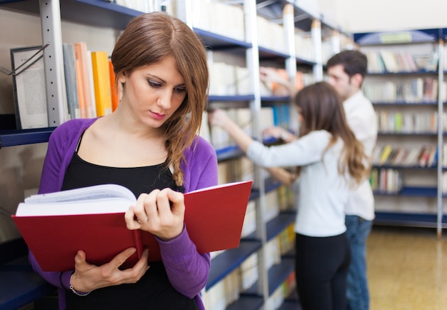 Frau, die ein Buch in einer Bibliothek liest