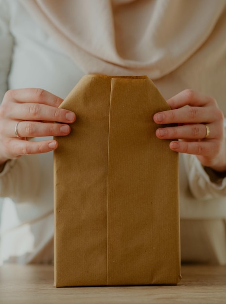 Frau, die ein Buch in Kraftpapier als Geburtstagsgeschenk einwickelt - rustikales Thema