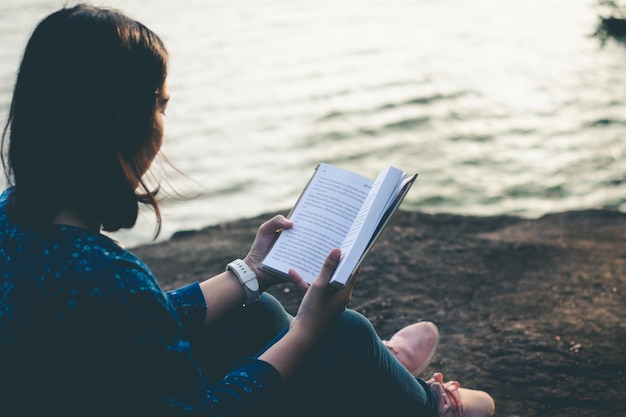 Frau, die ein Buch vor dem See liest