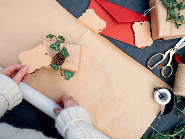 Frau, die ein Geschenk für ein Weihnachten auf einer Tabelle einwickelt