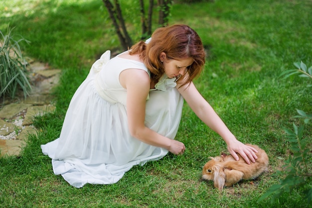 Frau, die ein Kaninchen im Garten streichelt