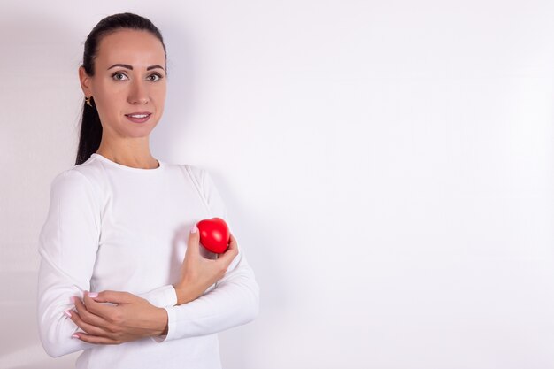 Frau, die ein rotes Herz in ihren Händen steht, die auf einem weißen Hintergrund stehen