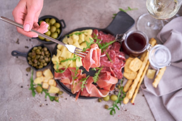 Frau, die ein stück prosciutto-schinken auf einer gabel hält, die in der heimischen küche steht