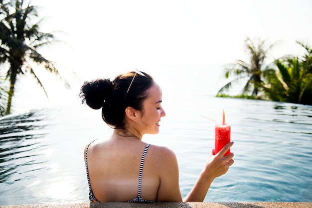 Frau, die ein wassermelonengetränk im pool genießt