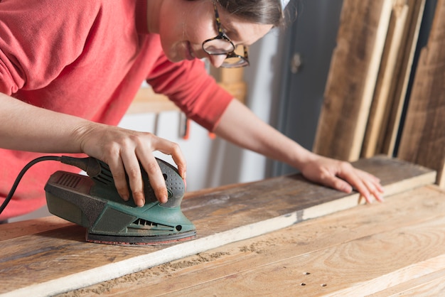 Frau, die ein wieder hergestelltes Holz versandet