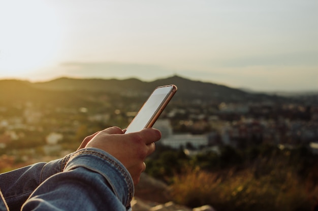 Frau, die eine App am Telefon am Herbstsonnenuntergang verwendet