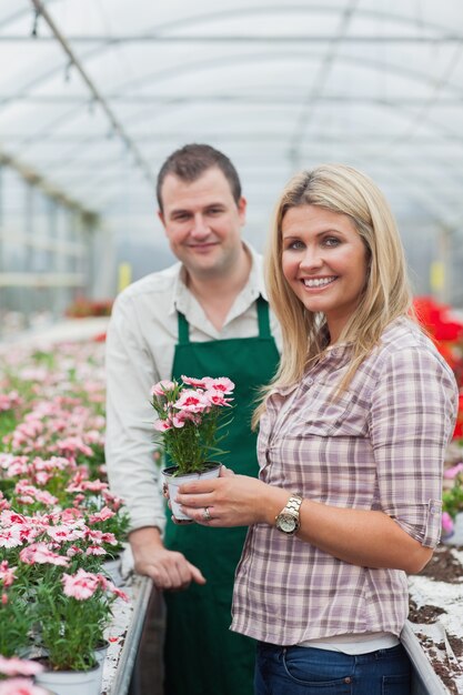 Frau, die eine Blume im Gewächshaus mit Angestelltem wählt