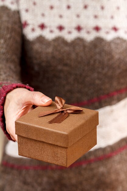 Frau, die eine Geschenkbox in der Hand hält. Geringe Schärfentiefe, selektiver Fokus auf die Box. Konzept, im Urlaub oder Geburtstag ein Geschenk zu machen.