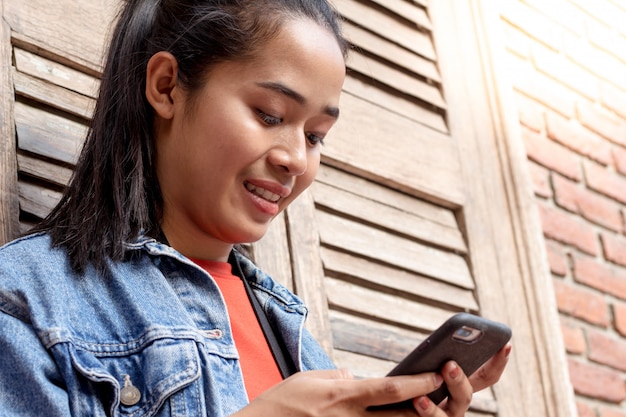 Frau, die eine Jacke trägt und mit Handy spielt