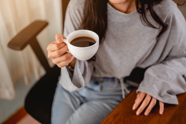 Frau, die eine Kaffeetasse hält, arbeitet von zu Hause aus und wartet auf eine baldige Verbesserung der epidemischen Situation zu Hause. Coronavirus, Covid-19, Arbeit von zu Hause aus (WFH), soziale Distanzierung, Quarantäne, Konzept zur Infektionsprävention.