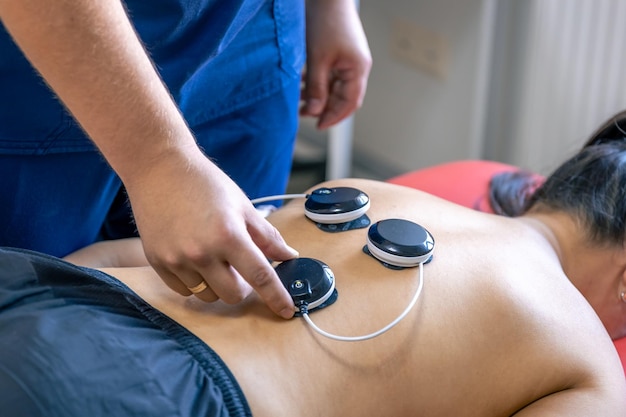 Foto frau, die eine myostimulationsbehandlung in einer physiotherapie-klinik erhält