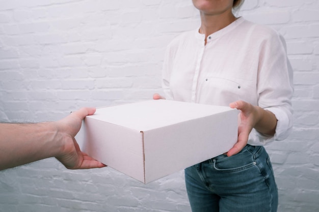 Frau, die eine Sendung von einem männlichen Kurier erhält Frau, die ein Paket von einem Kurier zu Hause erhält