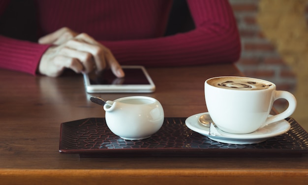 Frau, die eine Tablette mit Kaffeetasse auf Holztisch verwendet.