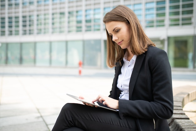 Frau, die eine Tablette vor ihrem Büro benutzt