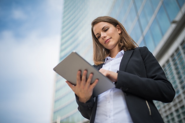 Frau, die eine Tablette vor ihrem Büro verwendet