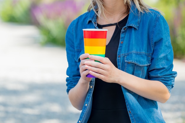 Frau, die eine Tasse in der Farbe der LGBT-Flagge in einem Park hält