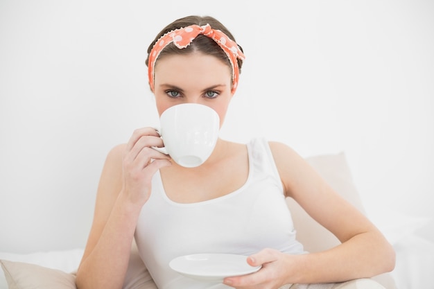 Frau, die eine Tasse Tee untersucht die Kamera trinkt