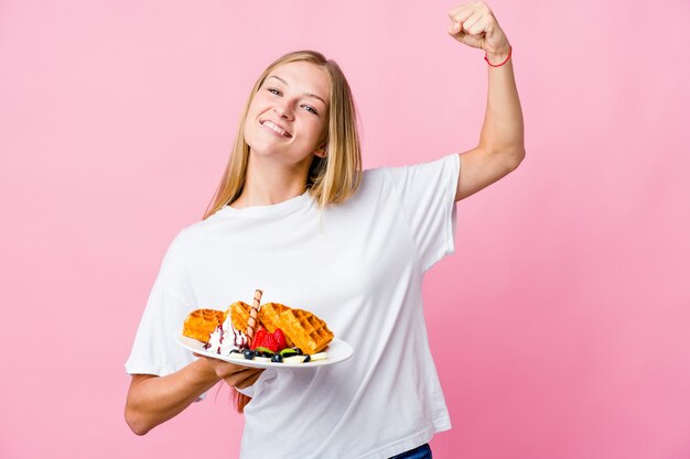 Frau, die eine Waffel isst, die Kraftgeste mit Armen zeigt