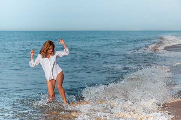 Frau, die eine Welle am Strand springt