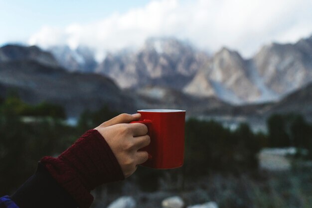 Frau, die einen Becher mit Blick auf die Himalaya-Berge hält