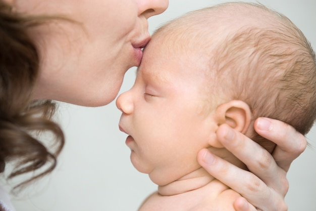 Frau, die einen den Kopf des Babys zu küssen