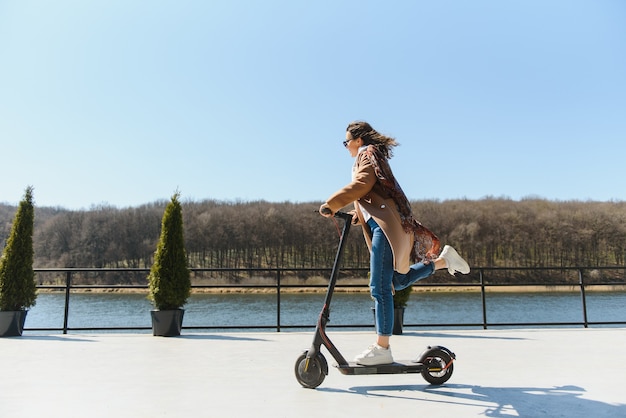 Frau, die einen Elektroroller im Freien reitet