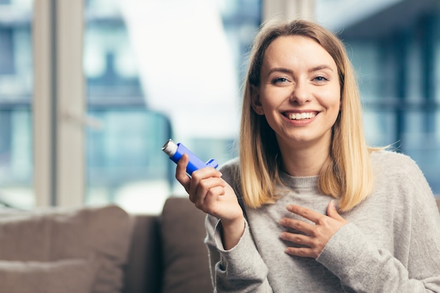 Frau, die einen Inhalator verwendet, während sie zu Hause an Asthma leidet