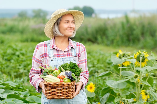 Frau, die einen Korb voller Ernte-Bio-Gemüse und Wurzel auf Bio-Bio-Farm hält. Herbstgemüseernte.