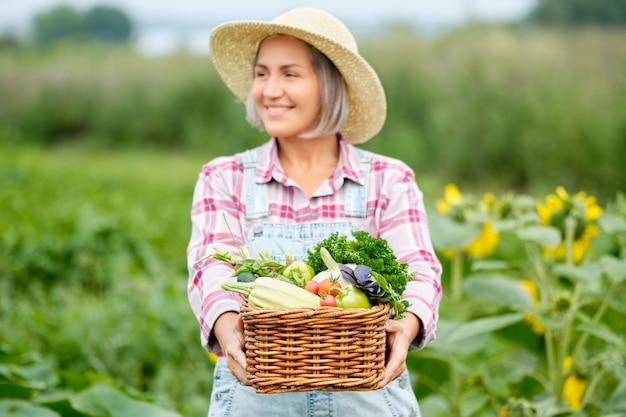 Frau, die einen Korb voller Ernte-Bio-Gemüse und Wurzel auf Bio-Bio-Farm hält. Herbstgemüseernte.