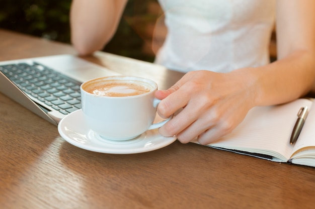 Frau, die einen Laptop während einer Kaffeepause verwendet