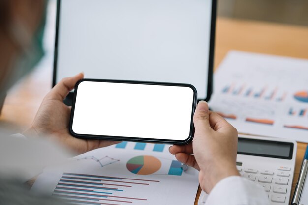 Frau, die einen leeren weißen Bildschirm des Smartphones im Büro hält.