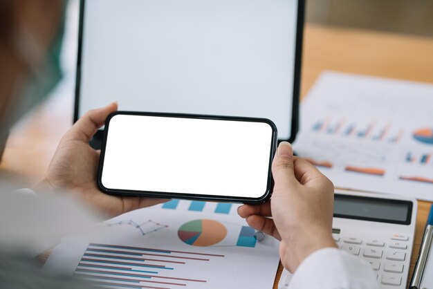 Frau, die einen leeren weißen Bildschirm des Smartphones im Büro hält.