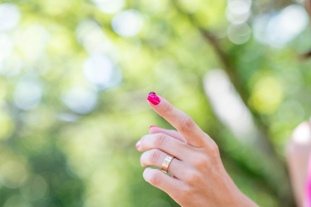 Frau, die einen Marienkäfer auf ihrem Finger anzeigt