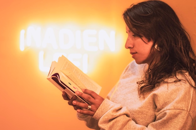 Frau, die einen Pullover trägt und ein Buch mit gelbem Licht liest