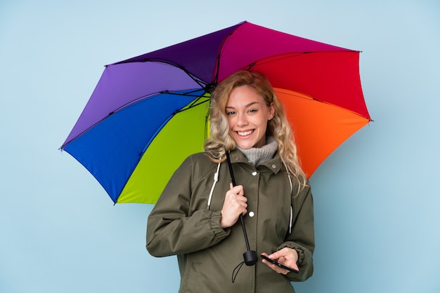 Frau, die einen Regenschirm auf Blau hält