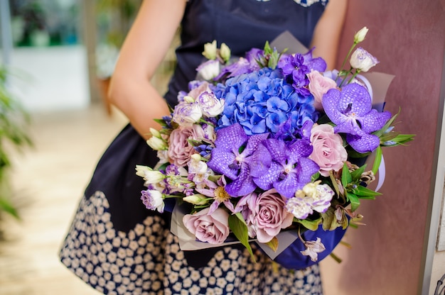 Frau, die einen schönen purpurroten und blauen Blumenstrauß von Blumen hält